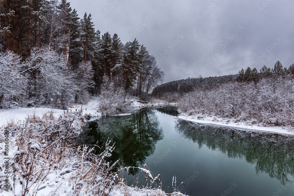 Obraz premium A cooling river with the first snow on the shore