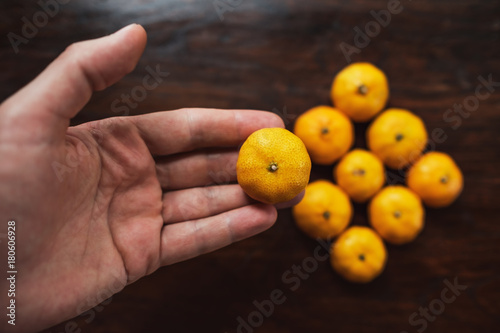 Hand holding mandarin on wooden table in rectangle shape.