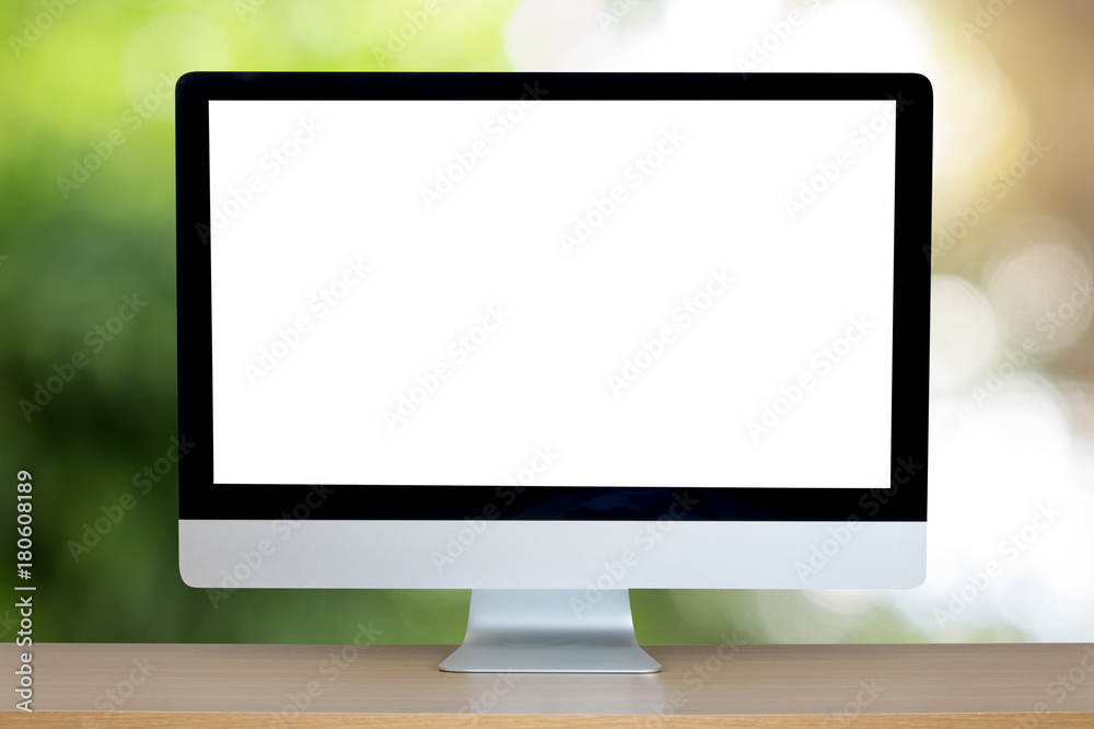 Computer over wooden table on natural green blurred background