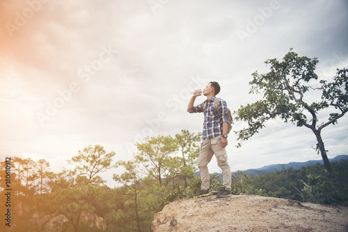 Happy hipster man tourist with backpack drinking water while hiking in nature forest.