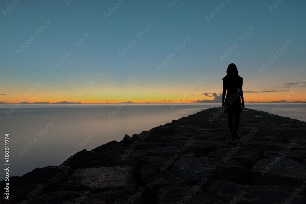 Silhouette of a woman walking by the sea Silhouette of a woman walking by the sea