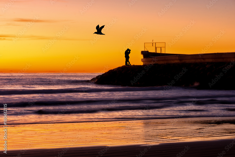 Silhouette of a couple kissing by the sea at sunrise