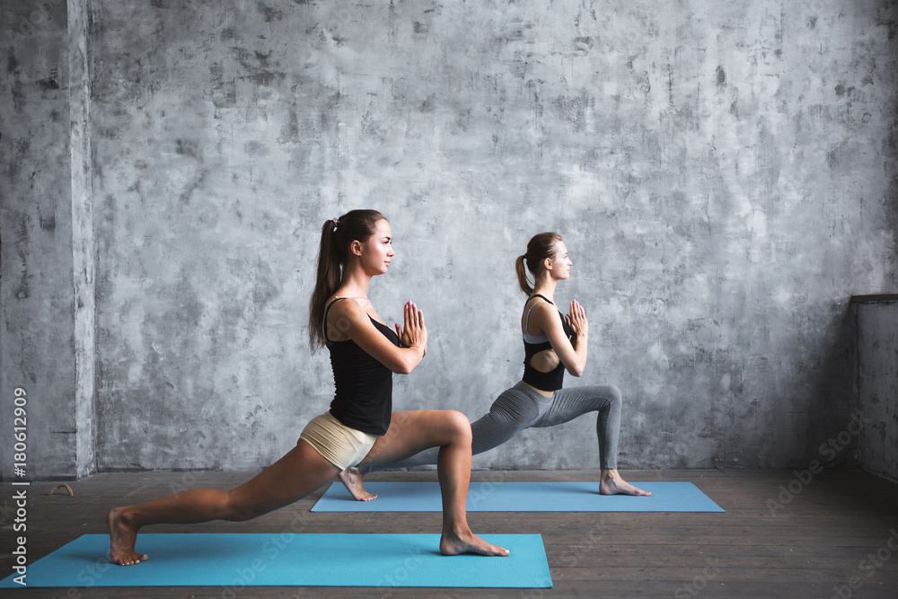 Acroyoga practice. Pair sporty yoga women doing exercise on gray stylish background. Acroyoga practice. Pair sporty yoga women doing exercise on gray stylish background.