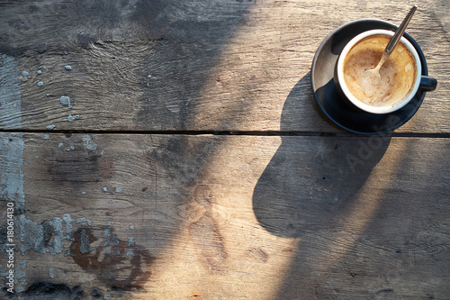 Empty cup of coffee with sunlight on wood table at vintage coffee shop