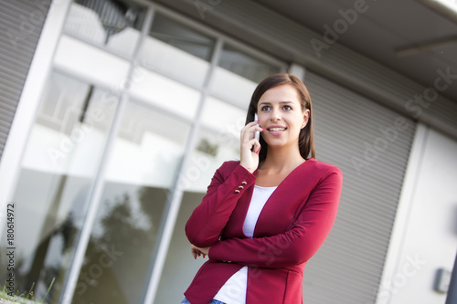 Young businesswoman in red blazer talking over the mobile phone