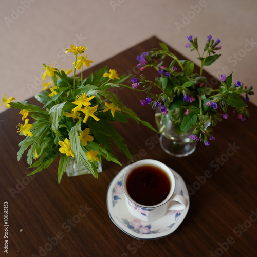 Two bouquets of flowers: yellow Venetian and purple Medunitsa, and a cup of tea. photo