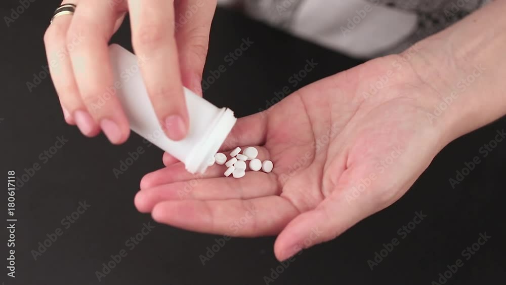 pills poured into a hand from a jar, close-up of female hands on a black background pills poured into a hand from a jar, close-up of female hands on a black background