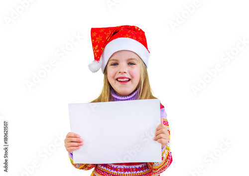 Счастливая девочка в шапке санта Клауса держит в руках пустой белый лист бумаги.