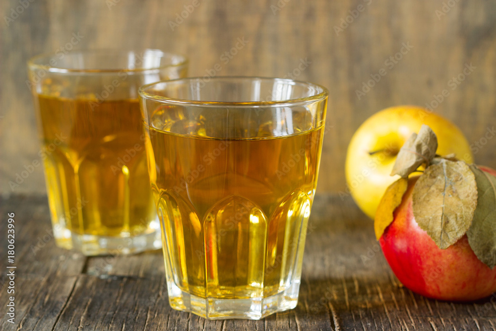 Apple juice in glasses and fresh apples on a wooden background. Rustic style. Apple juice in glasses and fresh apples on a wooden background. Rustic style.