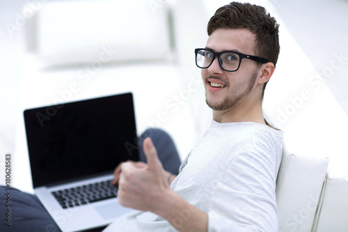 modern young sitting in front of the open laptop and showing thumb up