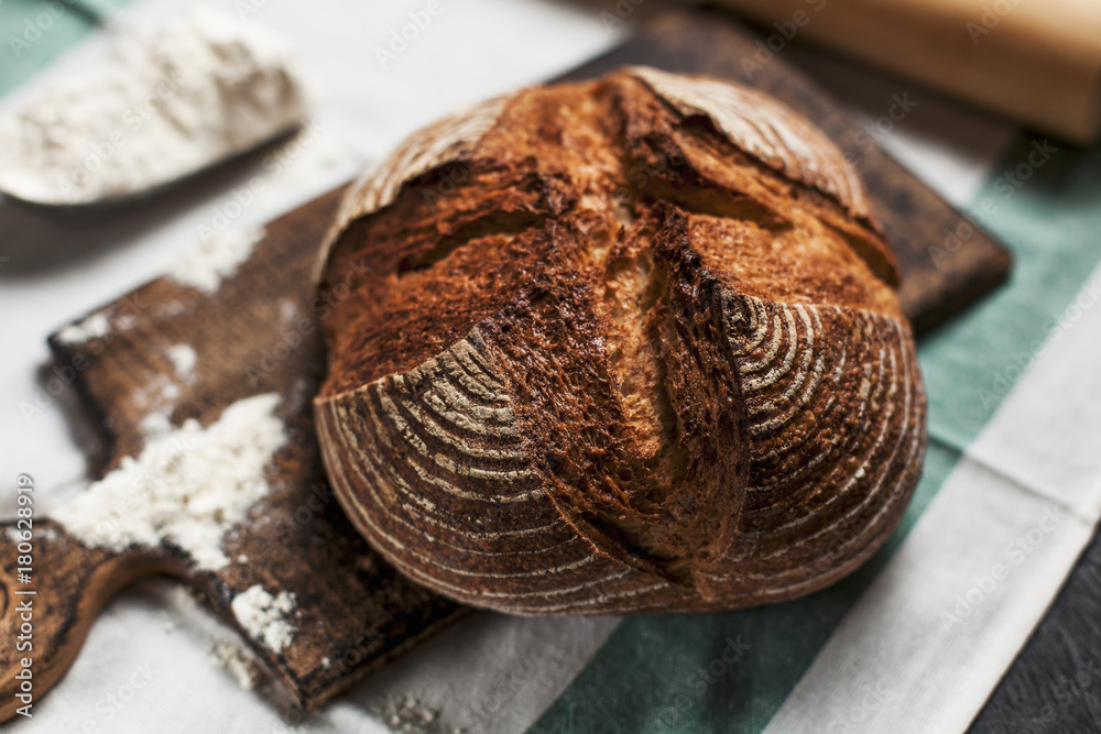freshly baked bread and flour on a wooden board on a kitchen towel on a table freshly baked bread and flour on a wooden board on a kitchen towel on a table