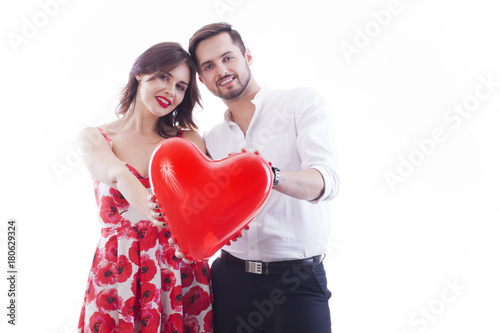 Love is in the air. Young couple is holding a heart balloon.