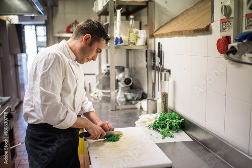 Handsome chef cook in uniform cooking food on the gas stove at the restaurant kitchen ..