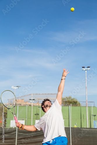 Professional tennis player throwing ball in the air before hitting it.  © pablobenii