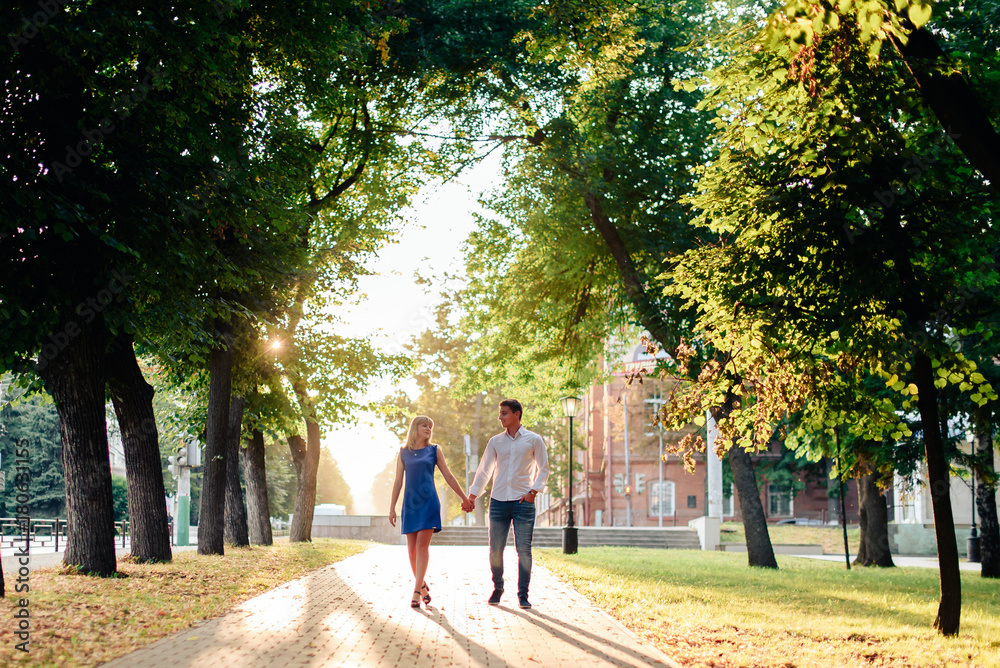 beautiful couple in love with a woman walking in a park on a bench kissing at sunset and loving each other, a blue dress and a white shirt with jeans