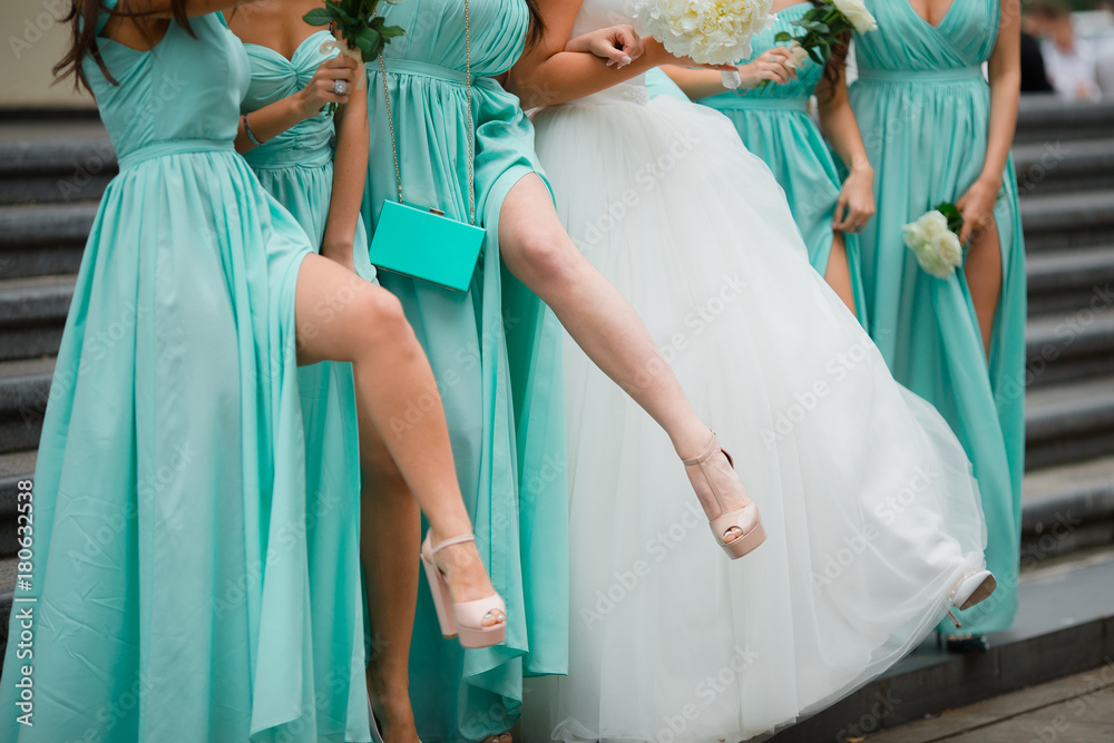 Bridesmaids legs. Dressed in blue dresses. On the background of stairs.