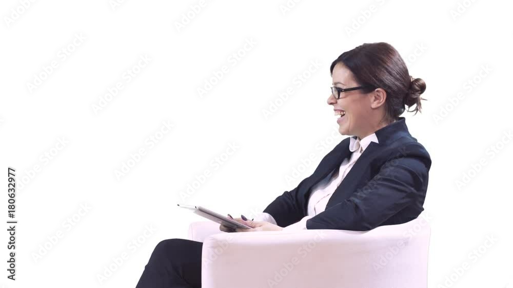 The TV Studio. Business woman with glasses sitting in the Studio in a business suit and gives interviews. Writes information on the screen and smiles. White background. The TV Studio. Business woman with glasses sitting in the Studio in a business suit and gives interviews. Writes information on the screen and smiles. White background.