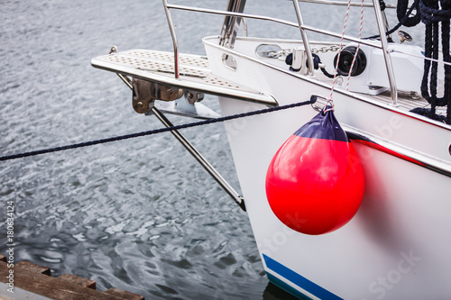 Fotografia Sailboat in the sea with red fenders buoy.
