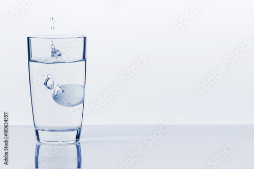 A soluble tablet dropped in a glass of water over white background