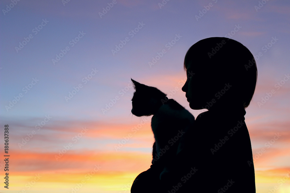 Children, pets, people and childhood concept. Cropped shot of a silhouette of a girl holding her kitten at sunset. Cropped shot of a cute little girl and kitten at sunset.
