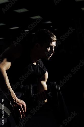 Strong Athletic Man Fitness Model Torso showing six pack abs. isolated on black background with copyspace Closeup of a handsome power athletic man bodybuilder doing exercises with dumbbell.