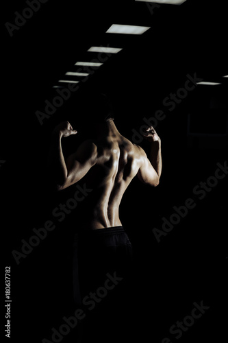 Strong Athletic Man Fitness Model Torso showing six pack abs. isolated on black background with copyspace Closeup of a handsome power athletic man bodybuilder doing exercises with dumbbell.