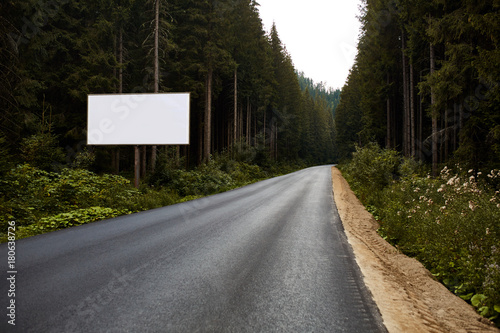 Canvastavla Blank billboard sign by empty highway through forest mountains landscape