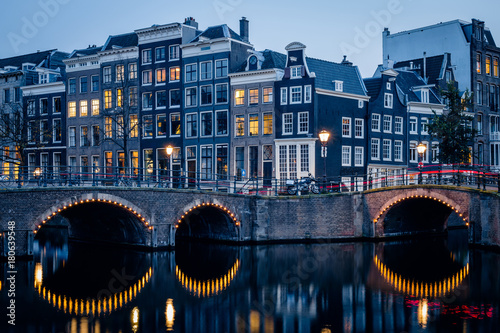 Old historic houses, canal, bridge and a red light trail during twilight blue hour, Amsterdam, Netherlands
