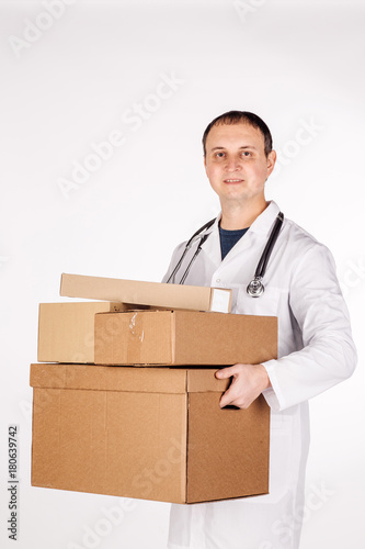 doctor smiling, holding box and looking at camera. image on a white studio background. © kaninstudio