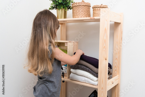 The girl is measuring her mother's clothes and shoes. Order in the closet. Smart storage system. Capsule wardrobe. The girl plays and puts things in order in her mother's things. Wardrobe order.