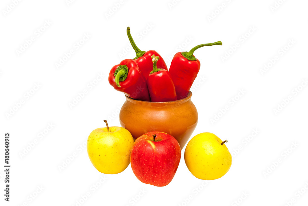 Red peppers in a brown ceramic pot and apples lying around, isolated on white background Red peppers in a brown ceramic pot and apples lying around, isolated on white background