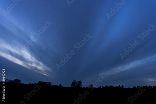 Evening sky with clouds and the silhouette of trees on the horizon