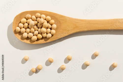 Soybean legume. Healthy grains on a wooden spoon. White background.