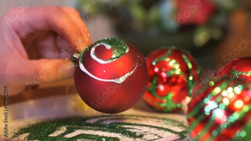 Female glittering a swirly glue pattern on a homemade Christmas bauble.