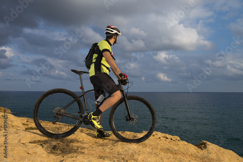 mountain biker looks at the sea from the rocks