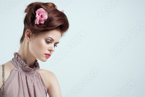 young woman on a light background with a flower in her hair, a lot of space to copy