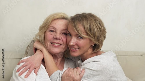 Happy adult daughter and old mother hugging and smiling