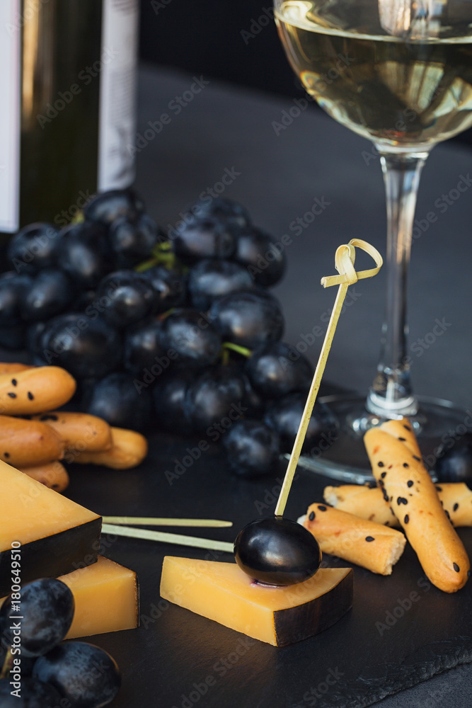 Cheese plate served with crackers, grapes and glass of white win Cheese plate served with crackers, grapes and glass of white win