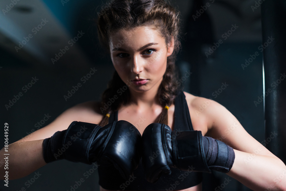 Young fighter boxer girl wearing boxing gloves before  training. She is looking at camera.