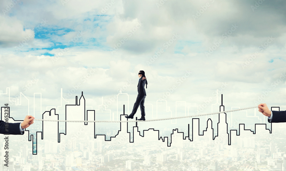Business concept of risk support and assistance with man balancing on rope Business concept of risk support and assistance with man balancing on rope