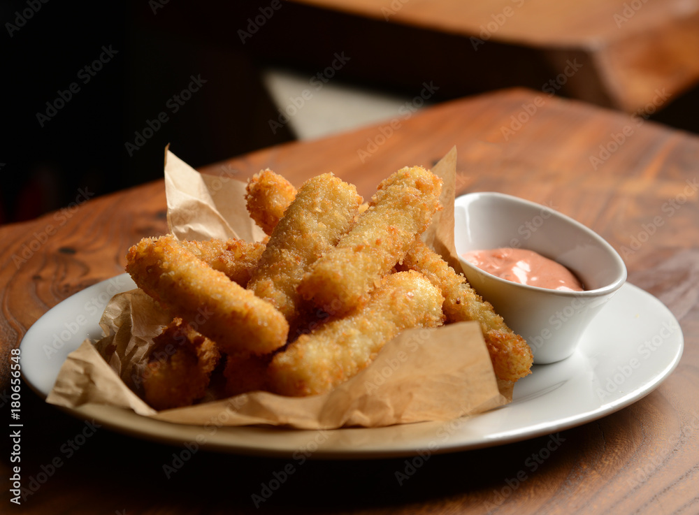 Delicious breaded mozzarella cheese sticks stack with hand pour marinara dipping sauce Delicious breaded mozzarella cheese sticks stack with hand pour marinara dipping sauce