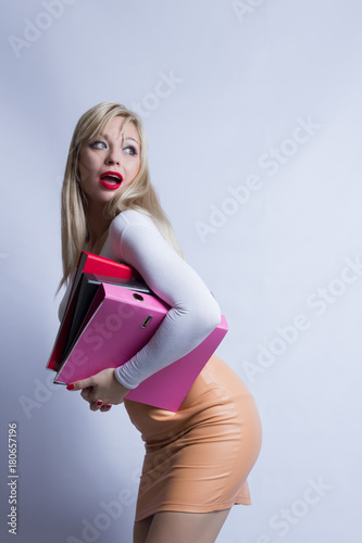 Business portrait of a beautiful young blond woman with long hair. The girl is dressed in a brown leather skirt and holds a folders photo