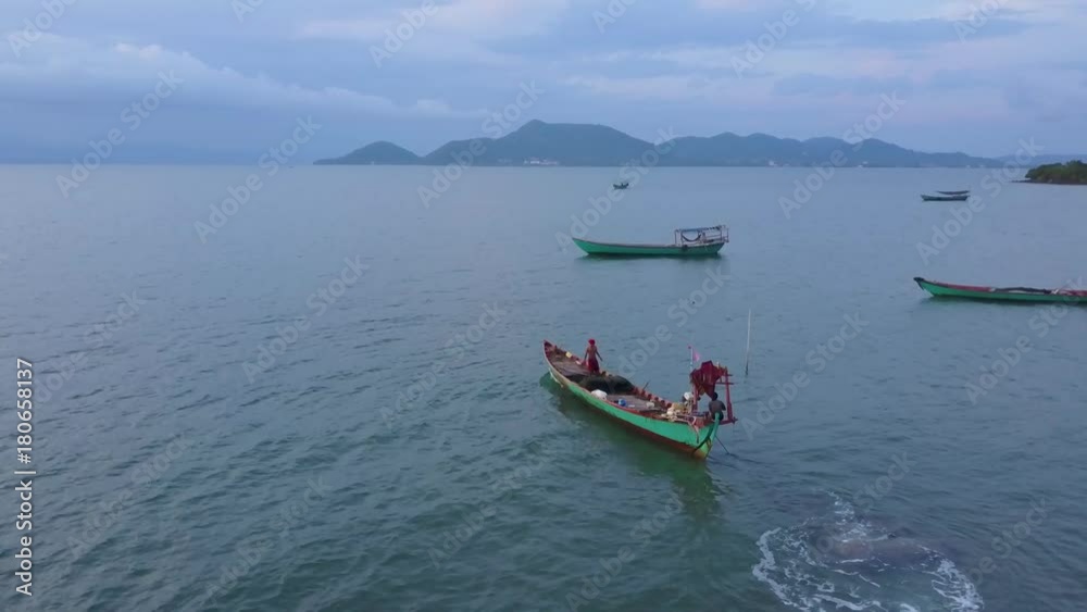 Aerial view of two fisherman start up their boat and motor out into the sea from Cambodia towards Vietnam. Aerial view of two fisherman start up their boat and motor out into the sea from Cambodia towards Vietnam.