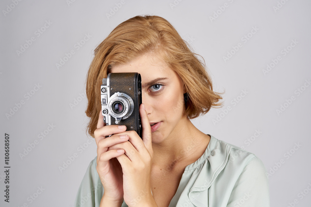 girl with short hair looks through a retro camera