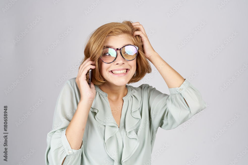 cheerful girl in big glasses with a phone on a light background cheerful girl in big glasses with a phone on a light background