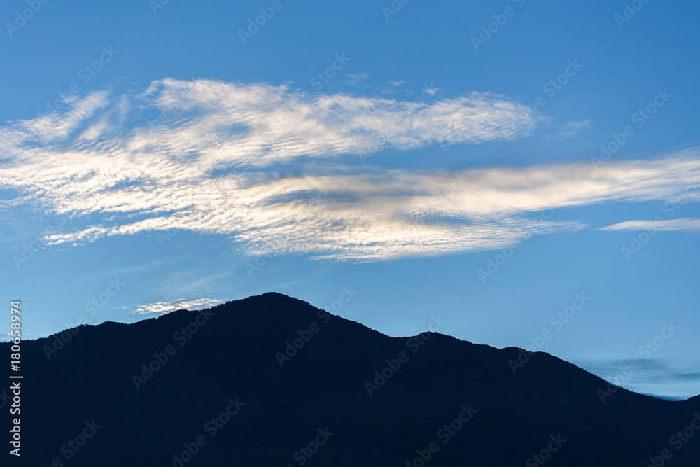 Silhouetted scene of mountain peak with slighly clouds and blue sky in morning. Mountain is in area of Sun Moon Lake, Taiwan. Silhouetted scene of mountain peak with slighly clouds and blue sky in morning. Mountain is in area of Sun Moon Lake, Taiwan.