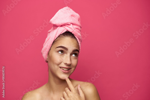 young woman with a towel on her head fooling around on a pink background