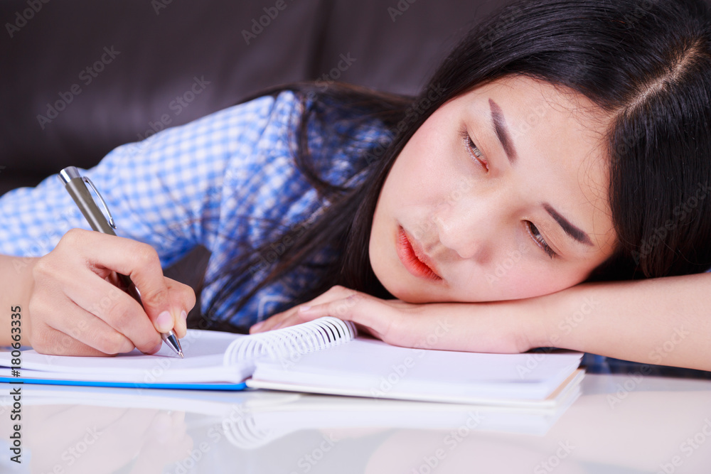 stressed business woman sitting at her desk and writes a note on the notebook stressed business woman sitting at her desk and writes a note on the notebook