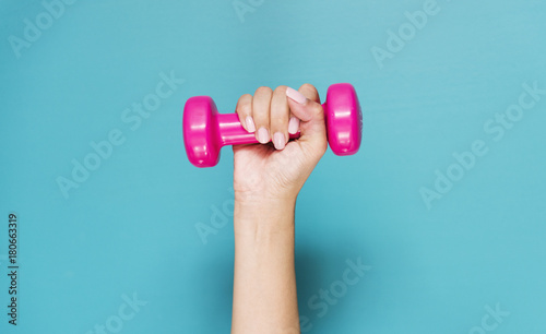 Closeup of hand holding pink dumbbell