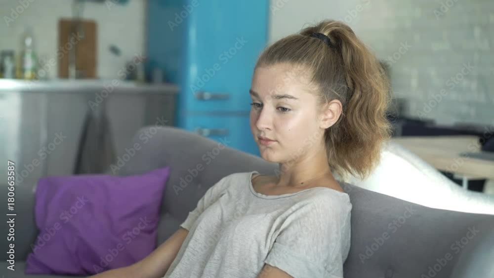 Sad, unhappy teenage girl sitting on sofa at home
Sad, unhappy teenage girl sitting on sofa at home